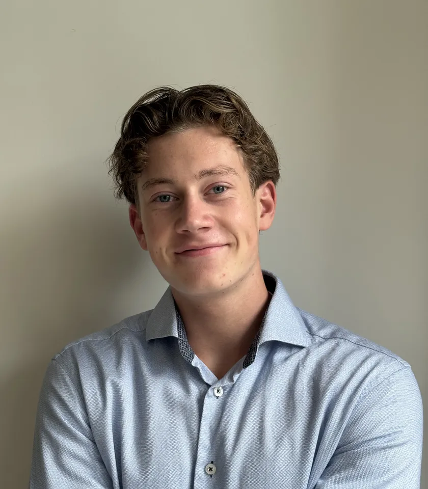 Maurits, oprichter van Flowvale, lachend in een lichtblauw overhemd voor een lichte muur.